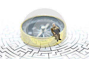 Miniature people : businessman sitting on compass with maze,Co