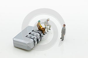 Miniature people: Businessman sitting on master key encoding. Image use for background security system, hack, business concept