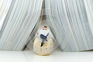 Miniature people: Businessman sitting reading newspaper on dice. Image use for think solution of business