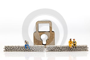 Miniature people: Businessman sitting on the wall and have master key is inside. Image use for business security center, protect