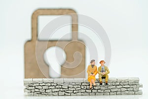 Miniature people: Businessman sitting on wall with master key. Concepts of finding a solution, problem solving and challenge