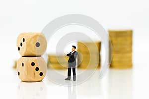 Miniature people: Businessman with stack of coins and dice . Image use for risk of business concept.