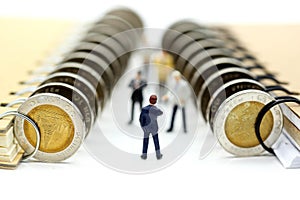 Miniature people : Businessman stand with coins of book,education or business concept.