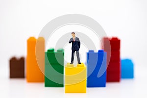 Miniature people: Businessman stand front of dashboard, display graphs, profit margins of background. Image use for business