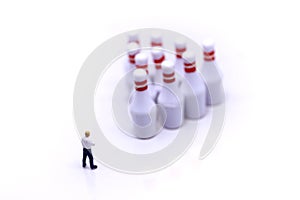 Miniature people : businessman stand with Group of Bowling Pins,business and sport concept.