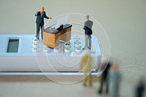 Miniature people businessman standing on calculator and talk to staff