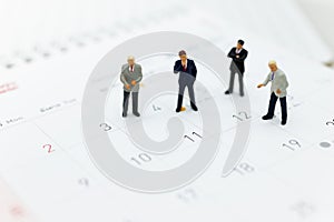 Miniature people : Businessman standing on the calendar to set the date for the meeting . Image use for business meetings concept