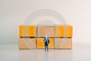 Miniature people, businessman standing with cartons box background