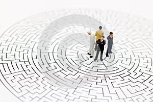 Miniature people: Businessman standing on center of maze. Concepts of finding a solution, problem solving and challenge. photo