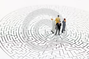 Miniature people: Businessman standing on center of maze. Concepts of finding a solution, problem solving and challenge.
