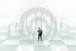 Miniature people: Businessman standing on the chess game, thinking solution for the business game, use as a business competition
