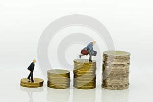 Miniature people : Businessman standing on a coin stacked increase up respectively. Image use for business concept.