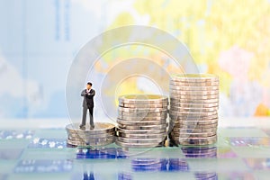 Miniature people : Businessman standing on a coin stacked increase up respectively, used as a business concept