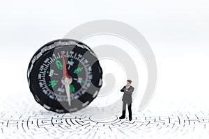 Miniature people : businessman standing with compass on maze paper. Image use for business concept