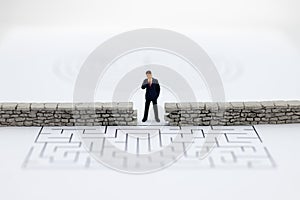 Miniature people: Businessman standing front of the wall and the world is inside. Image use for business security center, protect.