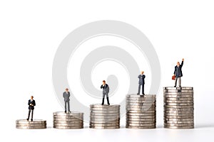 Miniature people: businessman standing stacking coins podium No.1, 2, 3, 4 and 5 isolated white background Financial and Business