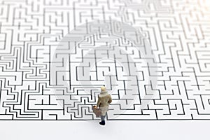 Miniature people: Businessman standing on start of maze.