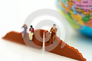 Miniature people: Businessman standing with wall and world. Concepts of finding a solution, problem solving and challenge