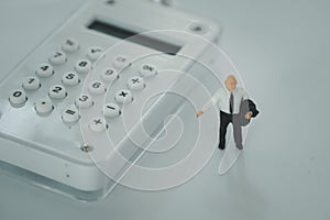 Miniature people: businessman standing on the white calculator. Financial and business concept