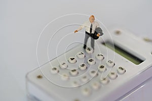Miniature people: businessman standing on the white calculator. Financial and business concept