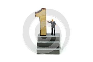 Miniature people : Businessman standing with wooden number of 1,to be the first,Business competition Concept.