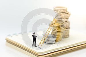 Miniature people: Businessman thinking and standing on stack of coins with stair. Image use for money growth up, business concept