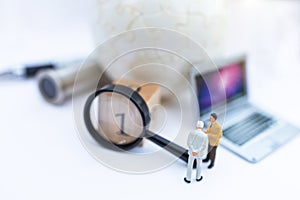 Miniature people: Businessman with  white globe and  laptop, use a magnifying glass to get number one. Recruitment finding