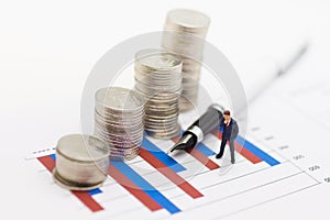 Miniature people : Businessmen earn profits from work, stack coins are placed on the graph. Use as a business concept