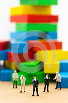 Miniature people: Businessmen stand looking at colorful building. Image use for Construction business