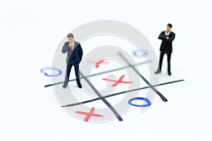 Miniature people: Businessmen stand on XO game board. Image use for business competition concept