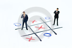 Miniature people: Businessmen stand on XO game board. Image use for business competition concept photo