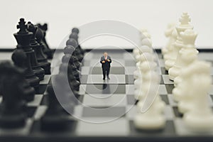 Miniature people businessmen standing on a chessboard with a chess piece on the back Negotiating in business. as background
