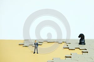 Miniature people businessmen standing in front of uncomplete jigsaw puzzles photo