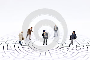 Miniature people : Businessmen standing on maze map and looking for a solution with teamwork. Image use for solve problems and new
