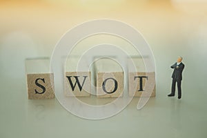 Miniature people businessmen standing with wood word SWOT. SWOT` analysis concept