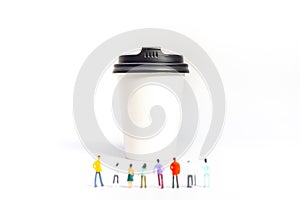 Miniature People and Coffee to-go Cup on white background. Cafe menu concept. Shallow depth of field