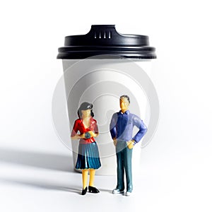 Miniature People and Coffee to-go Cup on white background. Cafe menu concept. Shallow depth of field