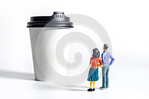 Miniature People and Coffee to-go Cup on white background. Cafe menu concept. Shallow depth of field