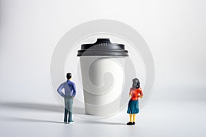 Miniature People and Coffee to-go Cup on white background. Cafe menu concept. Shallow depth of field