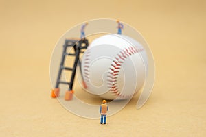 Miniature people Construction worker with baseball on Abstract background and red stitching baseball. White baseball with red