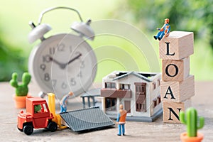 Miniature people Construction worker A model house model is placed with wood word LOAN and Vintage White Alarm Clock using as