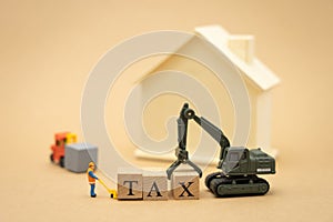 Miniature people Construction worker standing with wood word TAX using as background business concept and finance concept with
