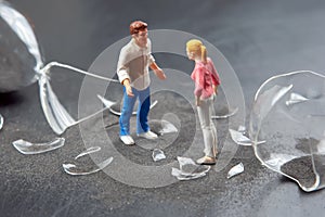 miniature people. couple of people near a broken hourglass. crisis of personal relationships. concept of communication and dispute