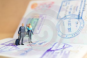 Miniature people couple standing on passport with immigration stamped