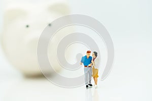 Miniature people: Couple standing with piggy bank