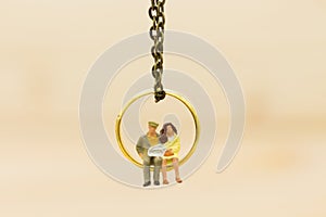 Miniature people : Couples sitting on the wedding ring. Image use for Valentine`s day.