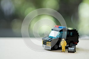 Miniature people crime investigators in hazmat suits with police car