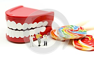 Miniature people : Dentist examining a patient`s teeth with patient and sweet lollipops,healthcare medical concept