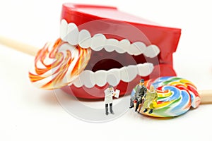 Miniature people : Dentist examining a patient`s teeth with patient and sweet lollipops,healthcare medical concept