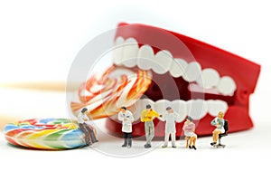Miniature people : Dentist examining a patient`s teeth with patient and sweet lollipops,healthcare medical concept